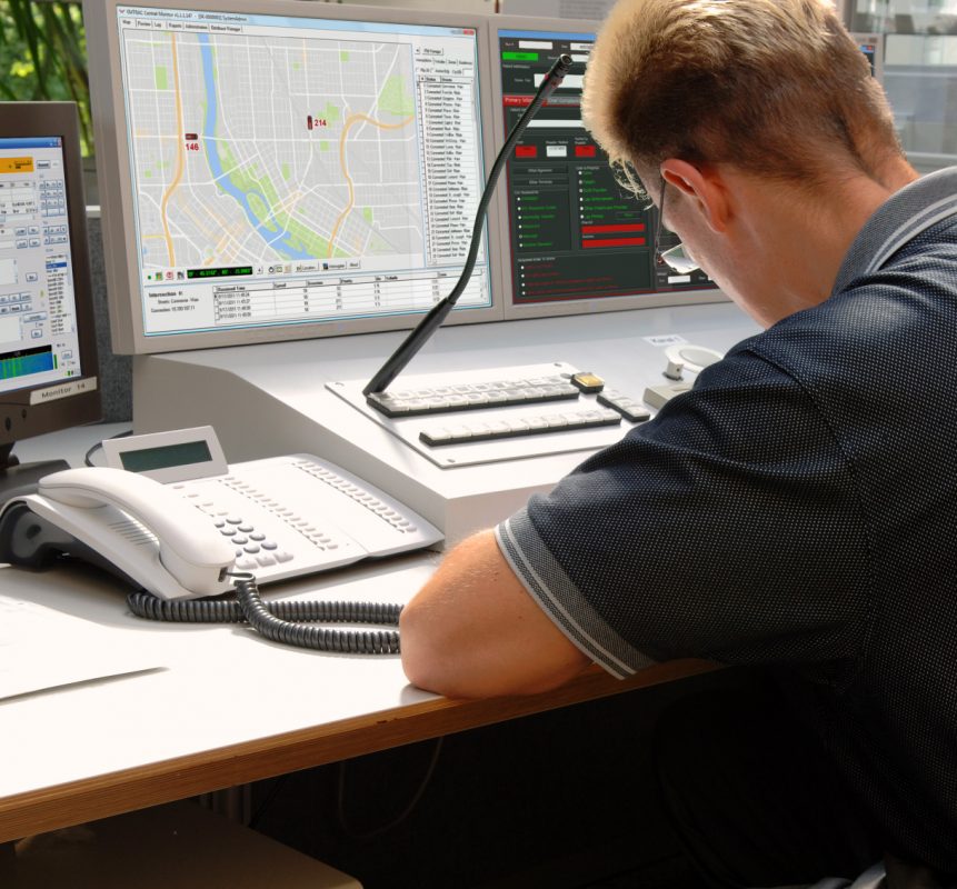 Supervisor at desk with monitor showing automatic vehicle locations for EMTRAC-connected vehicles